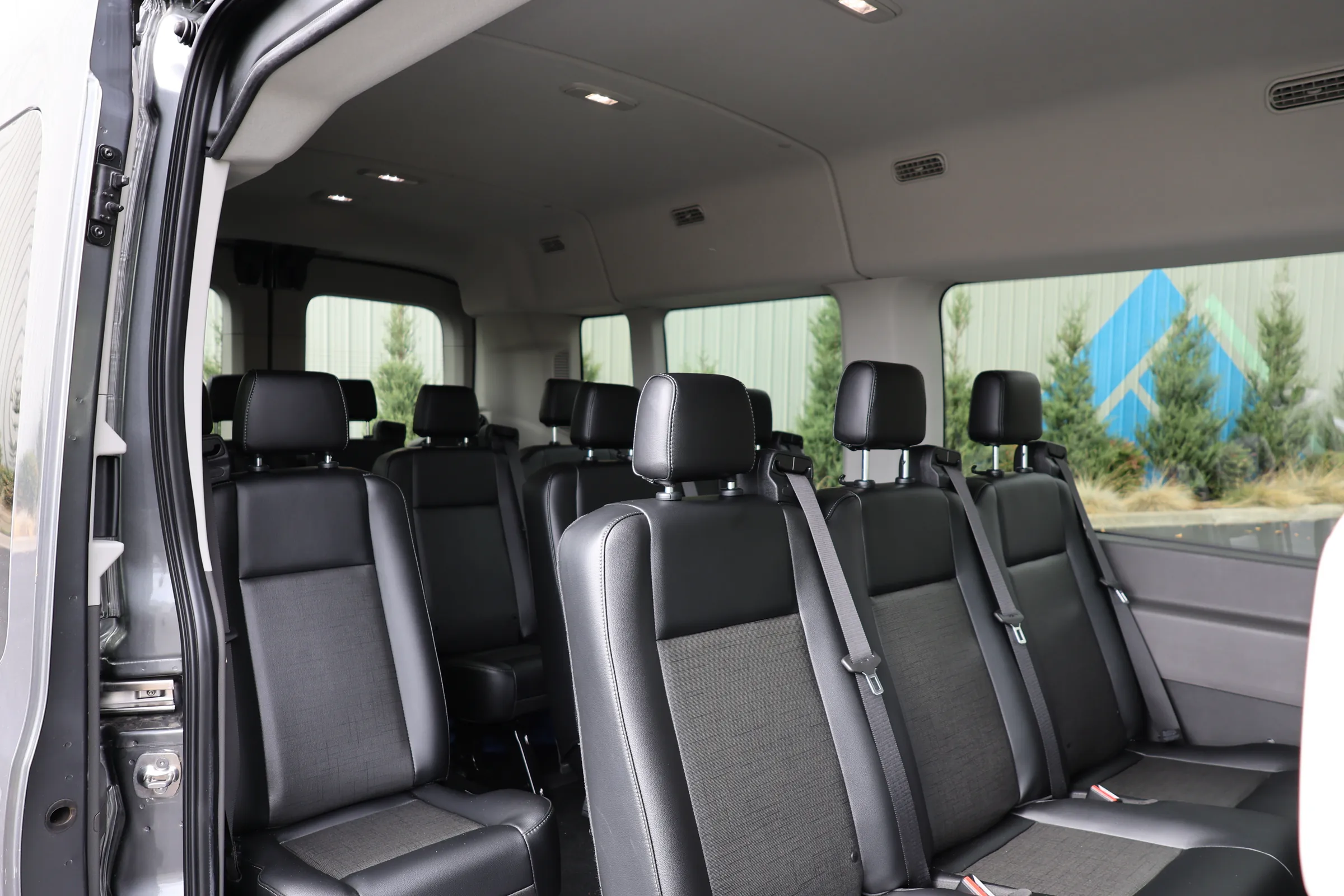 The inside of the van, with rows of individual seats and seat belts.